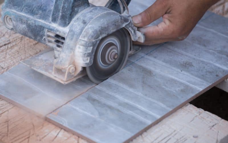 worker cutting a tile using an angle grinder