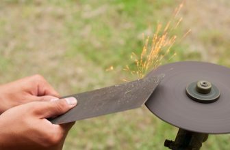 Man sharpening lawn mower blades with angle grinder